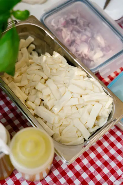 Natrhaná mozzarella fior di latte v nerezové misce na kostkovaném ubrusu