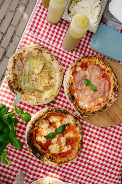 Tři neapolské pizzy na kostkovaném ubrusu, pohled shora